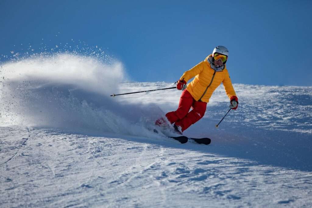 person in yellow jacket and red riding on snow ski